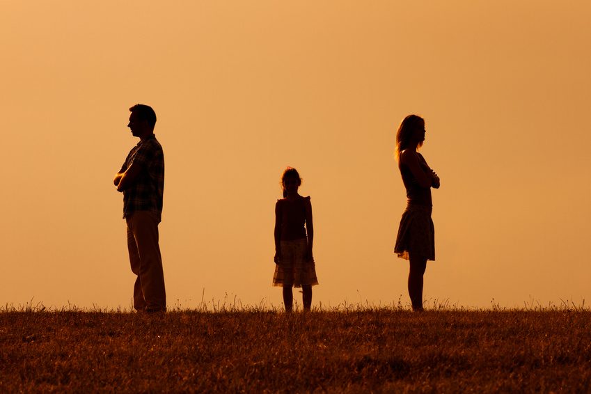 Silhouette of a angry husband and wife  on each other with their daughter standing in the middle.