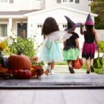 Three Children In Halloween Costumes Trick Or Treating