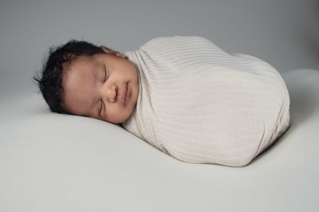 Wer ein Baby beruhigen möchte, sollte neben dem Einwickeln auch die Schlafposition anpassen