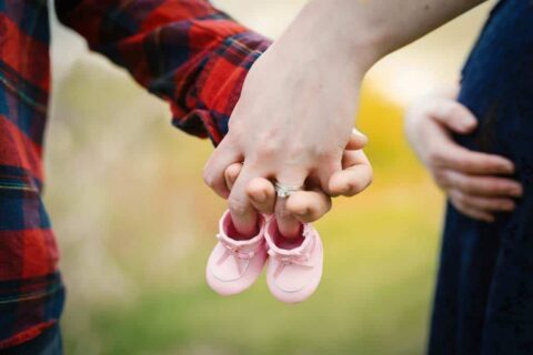 mann und frau halten babyschuhe